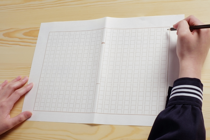 原稿用紙に文字を書く高校生
